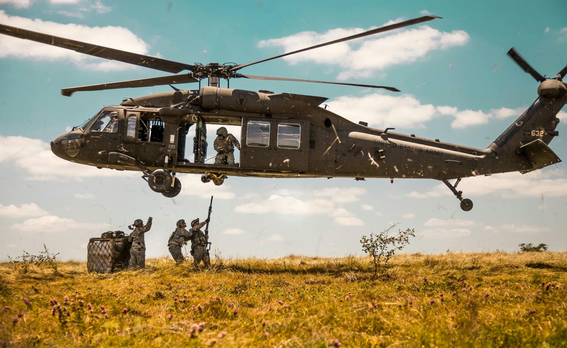 A Blackhawk helicopter in a military training mission with soldiers on a field.